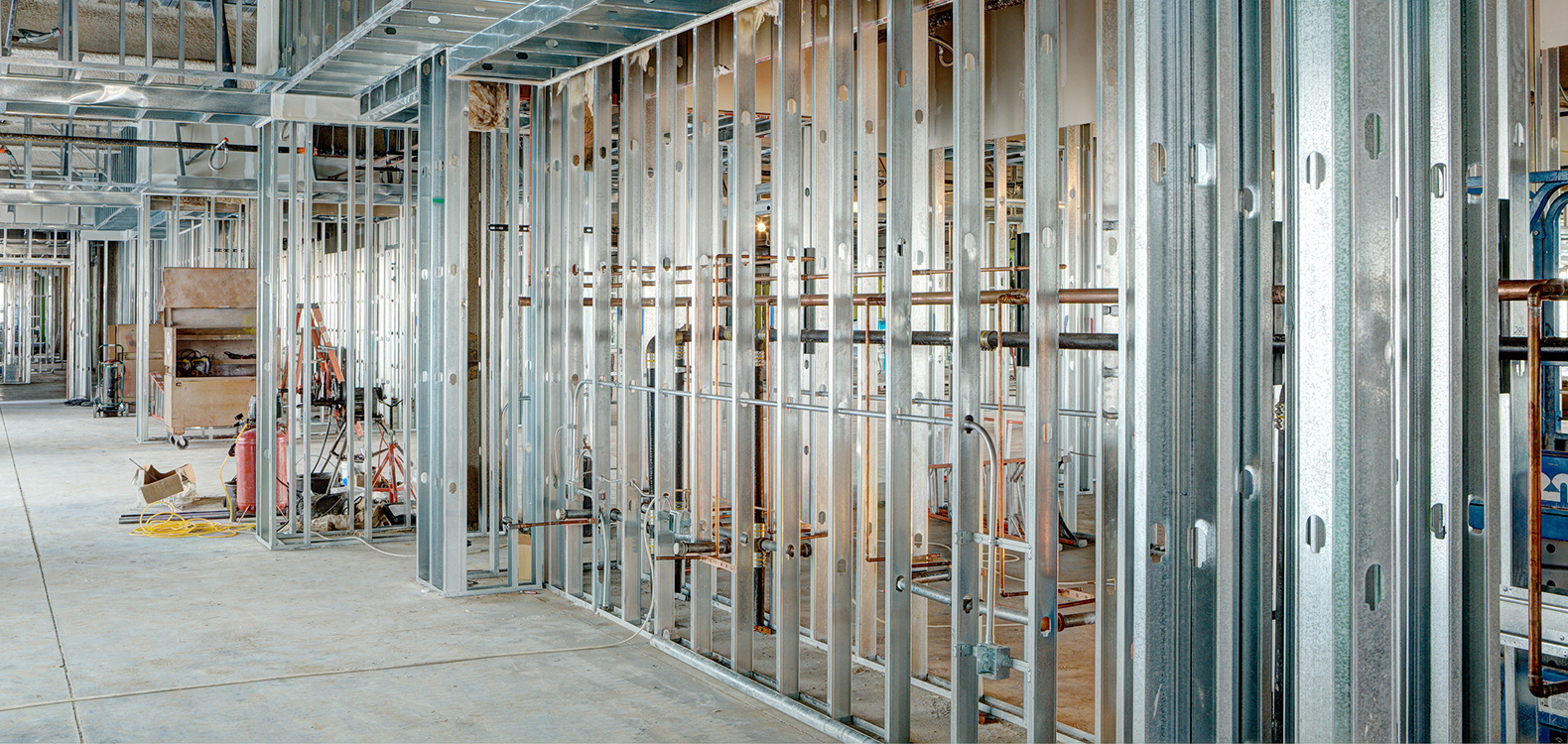 Metal framed walls down hallway on commercial construction project.