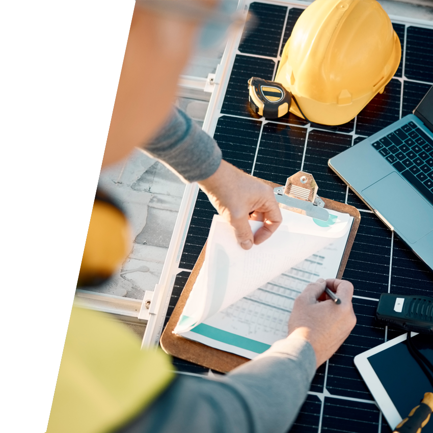 Man checking off items on construction paperwork attached to a clipboard with hard hat and construction tools nearby.